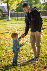 .Dad helps his son to blow bubbles in an autumn park.