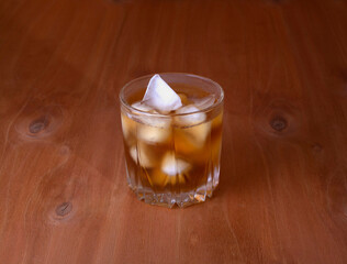 misted glass of whiskey with soft shadow on wooden background