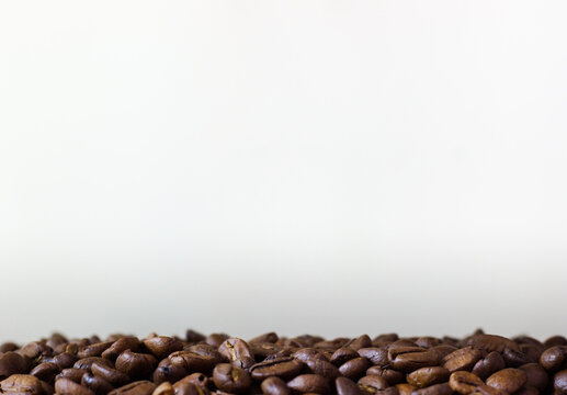 White pattern with coffee beans. Template with coffe on white background. Roasted coffee beans on white background. Heap of coffee beans. Poured coffee close up