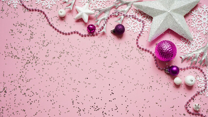 Christmas and New Year white stars,snowflakes and purple Christmas balls and decorations among sparkles on pink background,top view,flat lay,copy space,Christmas festive background. Festive postcard