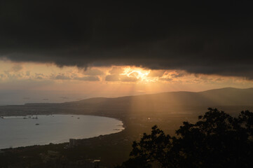 View of the Gelendzhik bay. View of the Black Sea. Dark clouds with the sun. Sunset over the clouds. September 2020