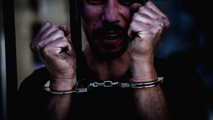 Handcuffed man imprisoned for crime, punished for serious villainy.