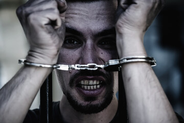 Upset handcuffed man imprisoned for crime, punished for serious villainy. Horizontal image.