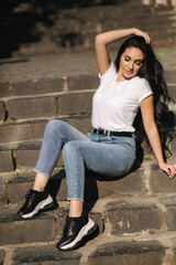 Sexy woman in denim sits on stairs in the city. woman with beautiful smile