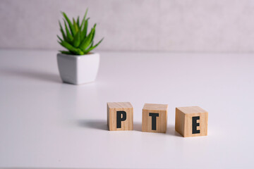 PTE - acronym from wooden blocks with letters, Pearson Tests of English PTE concept Foreign Language exams, top view on white background.