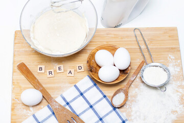making dough for bread or homemade baked goods. ingredients on a wooden table. inscription: bread