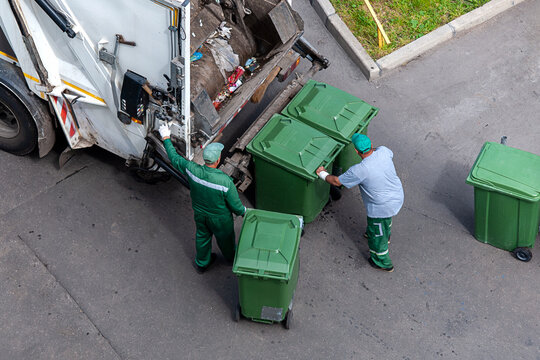garbage men loading household rubbish in garbage truck, view from above