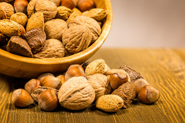 Mixed variety of nuts, walnuts, hazelnuts, almonds and macadamia nuts in a wooden bowl