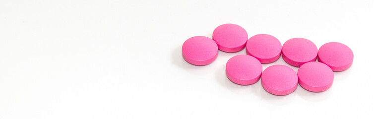 Close-up of pink round tablets on a white background, banner