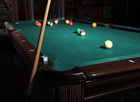 Cue Stick Leaning On Pool Table With Pool Balls Scattered