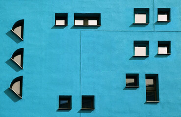 Fototapeta na wymiar Blue background with Windows, construction theme. Facade with small atypical windows on the facade of bluek color.