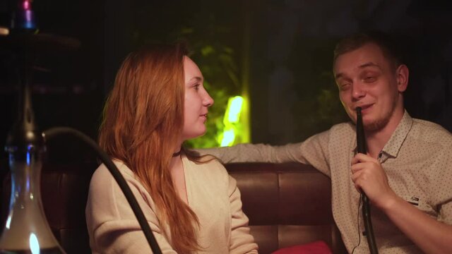 Man talking to his girlfriend with hookah pipe in bar. Media. Celebration, party concept, couple man with girl at shisha cafe lounge bar, date, love, relationship.