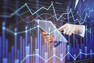 Double exposure of man's hands holding and using a digital device and forex graph drawing. Financial market concept.