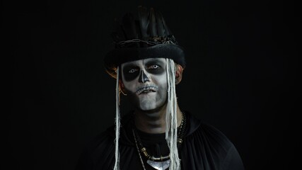 Scary guy in carnival costume of Halloween skeleton against black background. Man skull makeup