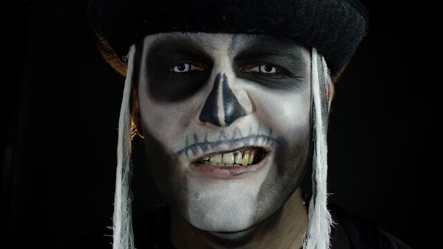 Man with skeleton makeup trying to scare, opening his mouth and showing dirty black teeth