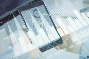 Double exposure of man's hands holding and using a phone and financial graph drawing. Analysis concept.