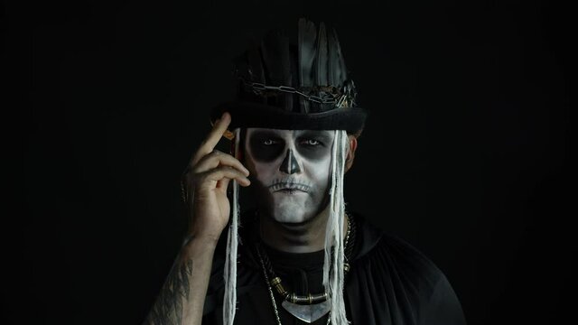 Man in scary halloween skeleton makeup making faces, smiles terribly. Voodoo rituals. Baron Saturday