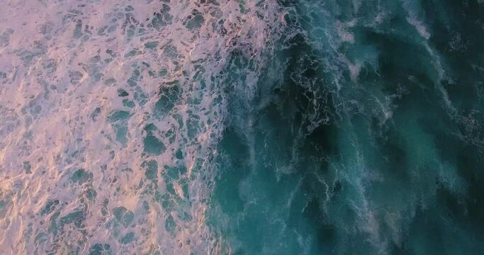 Overhead aerial, colorful sunset over ocean waves