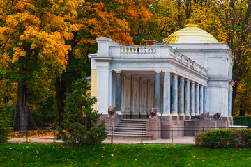 An old building with columns in an autumn Park against a background of red leaves.