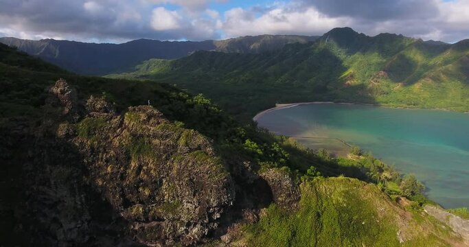 Woman hikes with view of Hawaiian coastline, wide aerial