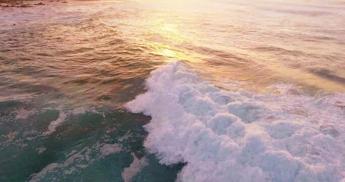 Tilt up aerial, ocean waves at sunset