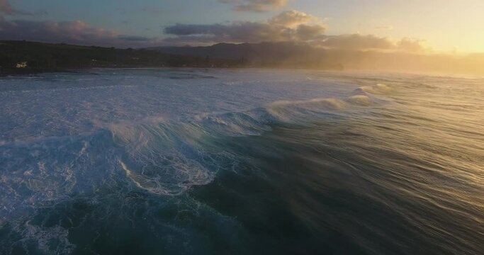 Wide panning aerial, sunset over ocean waves in Hawaii