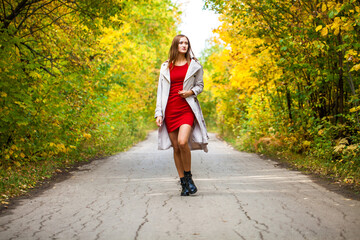 Young woman in red tight dress posing in autumn forest