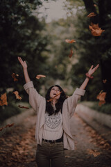 Girl smiling and throwing autumn leaves very happy