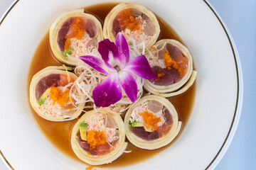 Overhead view of assorted raw fish arranged in suhshi roll encased with cucumber delicately presented on a plate to eat.