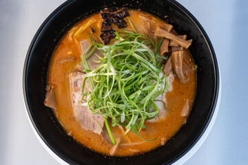 Overhead view of large bowl of spicy chashu ramen topped with bamboo shoots with delicate presentation for serving