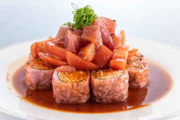 Ahi tuna stacked upon California roll and tomatoes delicately presented on a plate to eat