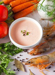Bowl of shrimp bisque surrounded by fresh ingredients