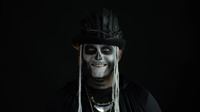 Creepy man with skeleton makeup in top-hat. Guy making faces, toothy smile. Halloween thematic party