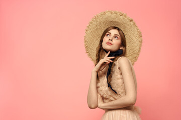 Fashionable woman in dress and hat with black ribbon on pink background cropped view of model emotions fun