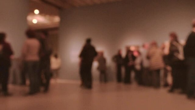 View of people walking during an art gallery exhibition visit. Background with an intentional blur effect applie. 4K