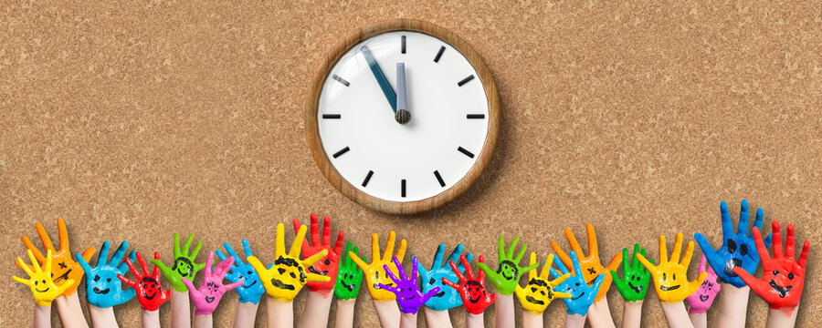 painted kids hands with smiley emoticons in front of cork background with a clock