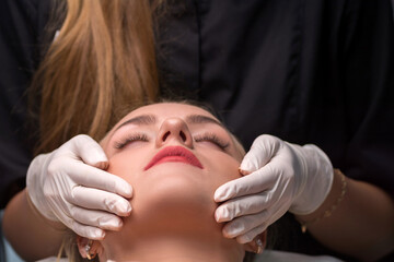 Young woman in a beauty salon. The beautician makes a facial cleansing procedure. Focus on lips