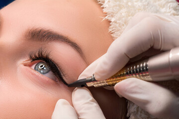 Permanent eye makeup close up shot. Cosmetologist applying tattooing of eyes. Makeup eyeliner...