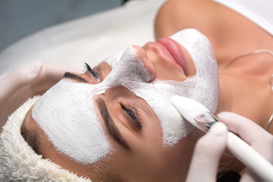 Applying a mask to the face in a beauty salon. Cosmetologist and procedure for rejuvenation and moisturizing.