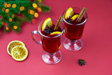 Hot mulled wine with cinnamon cardamom and anise on a red background.  Christmas  and new year composition.