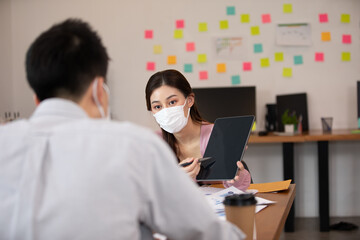Business man and woman wearing face mask meeting and working together for discussion and brainstrom to get ideas or marketing solution with social distance due COVID-19 virus flu pandemic and protect
