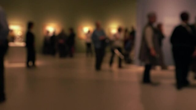 View of people walking during an art gallery exhibition visit. Background with an intentional blur effect applie. 4K