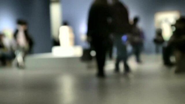 View of people walking during an art gallery exhibition visit. Background with an intentional blur effect applie. 4K