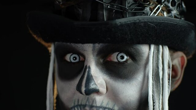 Close-up of scary man face in carnival skull Halloween makeup of skeleton looking creepy at camera