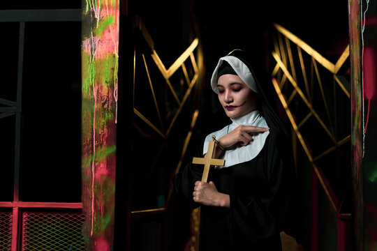 Scary woman devil nun holding a cross. Horror Halloween concept