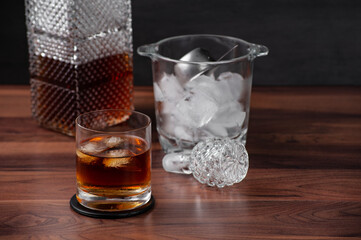Glass of whiskey and ice, ice bucket, bottle cap. Select focus