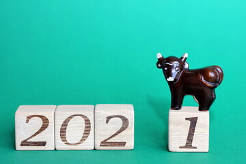 The bull is a symbol of the New year 2021. A toy broun bull is located on the wooden blocks with...