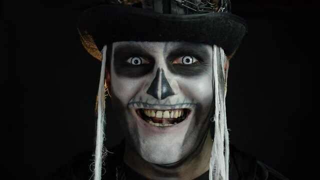 Creepy man face in skeleton Halloween cosplay appearing on black background. Making faces, smiling