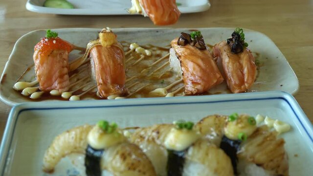 Chopsticks eating Japnese food aburi salmon nigiri with different sauces