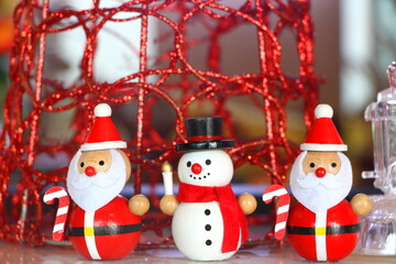 Close up santa claus hold candy cane and snowman wood toy on Christmas environment background, have copy space for put text.